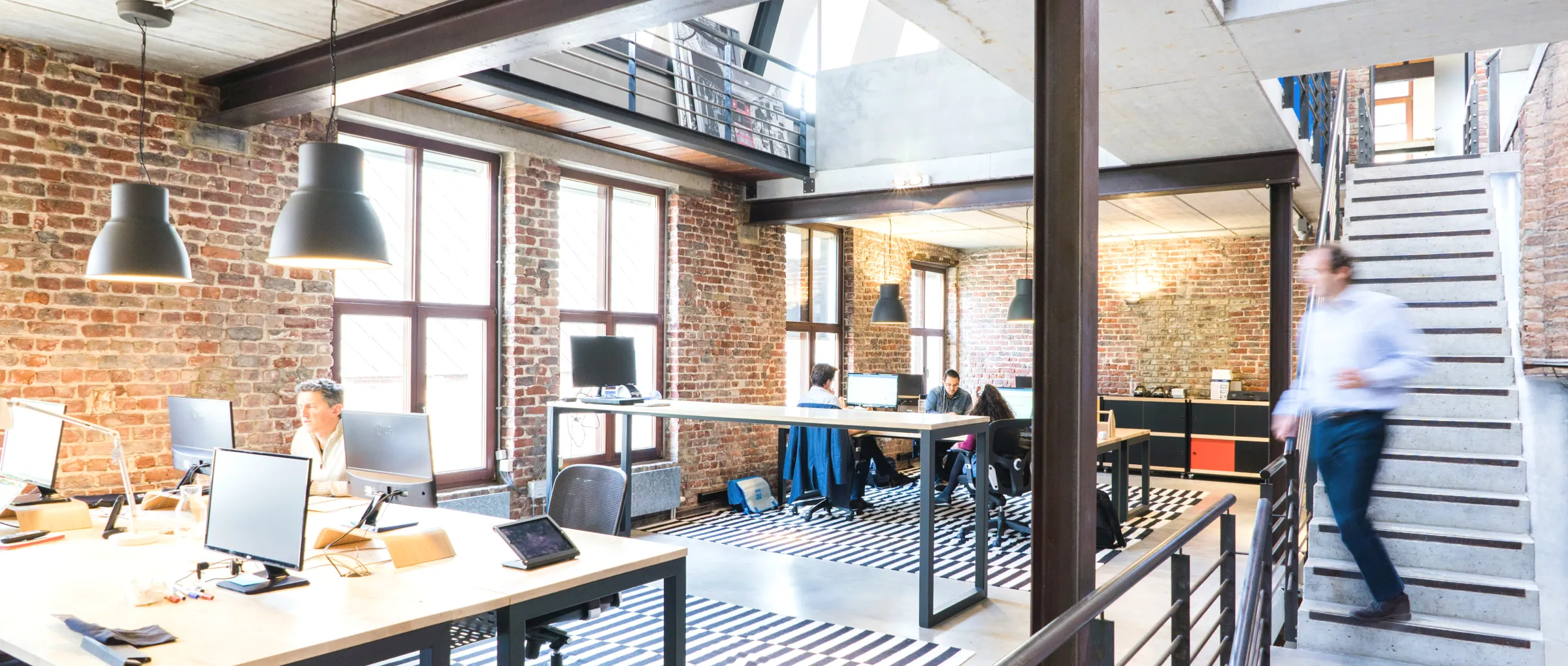 Open-plan, warehouse style office filled with computers and people