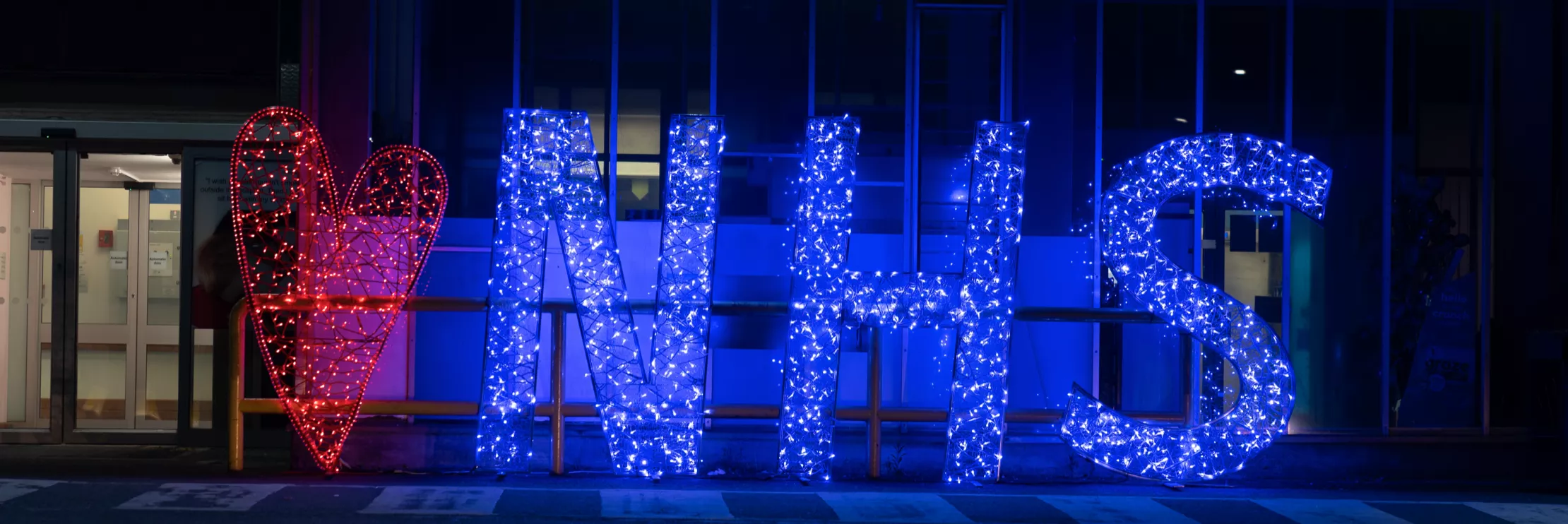 A heart and NHS sign lit up with fairy lights